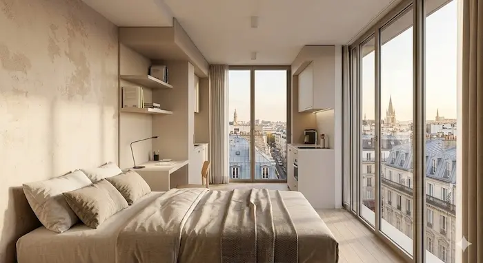 Une vue intérieure d'un studio meublé chaleureux et moderne situé au 10ème étage d'un foyer de jeunes travailleurs (FJT) à Paris 18ème, surplombant la ville à travers une grande fenêtre panoramique.