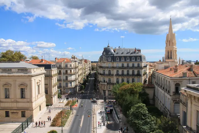 Vue extérieure d’une résidence étudiante moderne à Montpellier avec étudiants, tramway à proximité et architecture urbaine lumineuse du sud de la France.