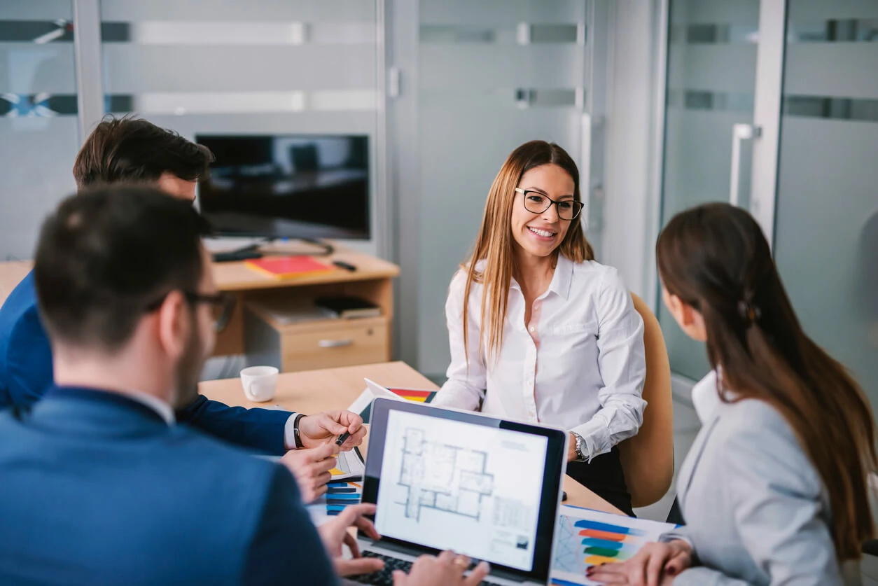 Quatre personnes consultant des dossiers autour d'un bureau.