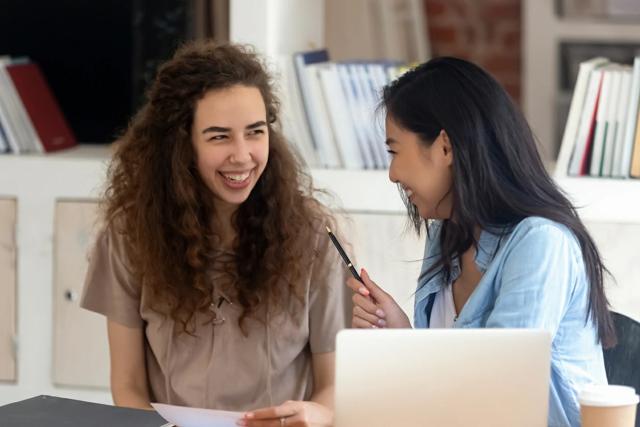 Deux jeunes femmes avec des airs joyeux devant un ordinateur portable.