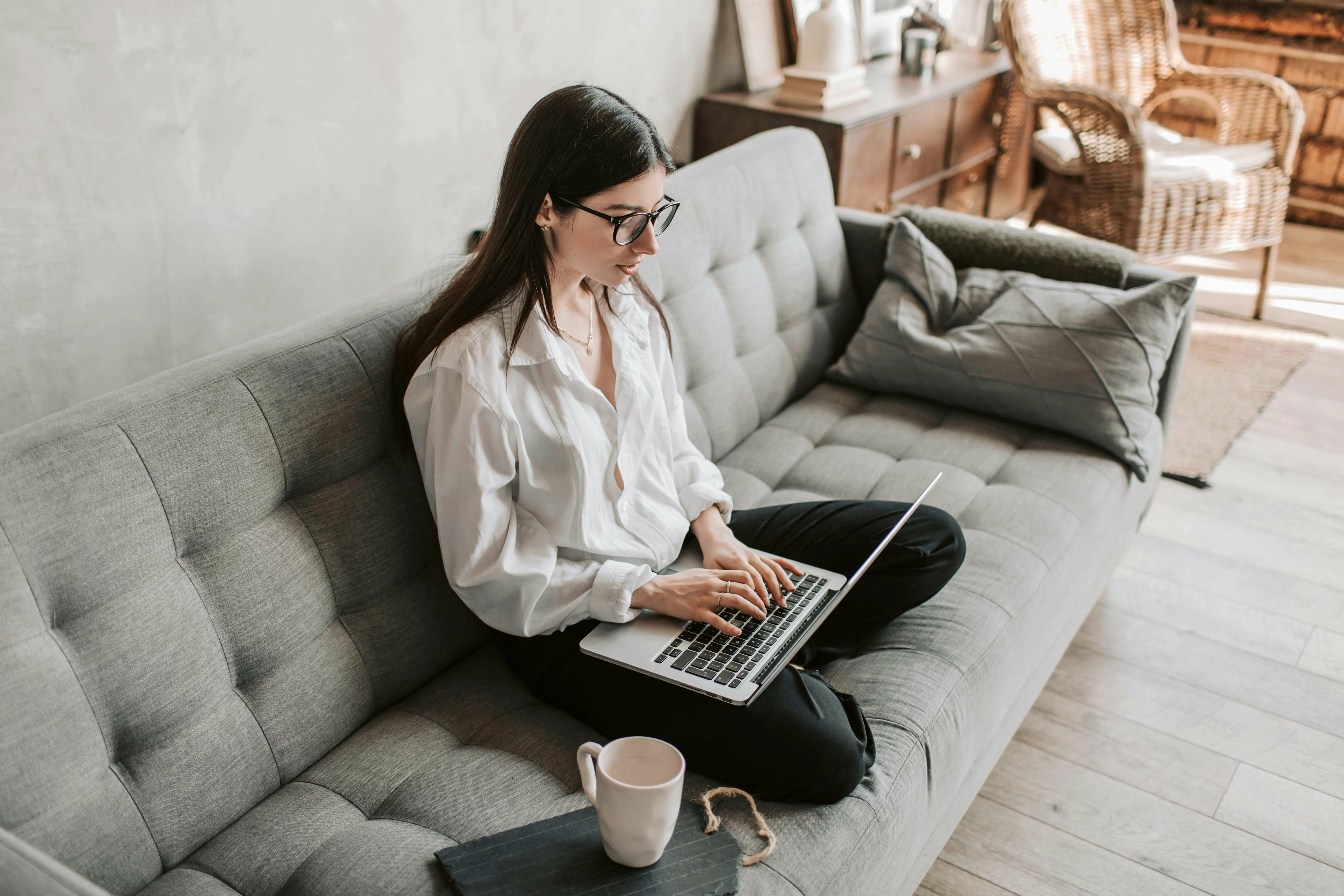 Jeune femme assise sur un canapé devant son ordinateur portable.