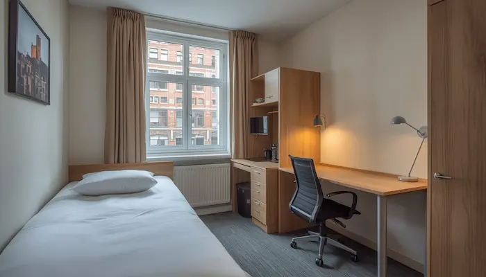 Chambre étudiante CROUS à Roubaix avec mobilier fonctionnel, lumière naturelle et vue urbaine rappelant l’ambiance du Nord.
