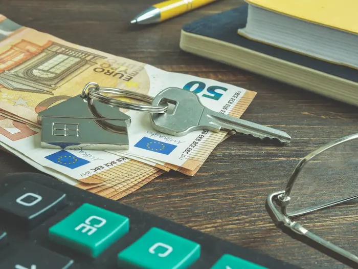 Calculatrice, liasses de billets, clé de maison et stylo