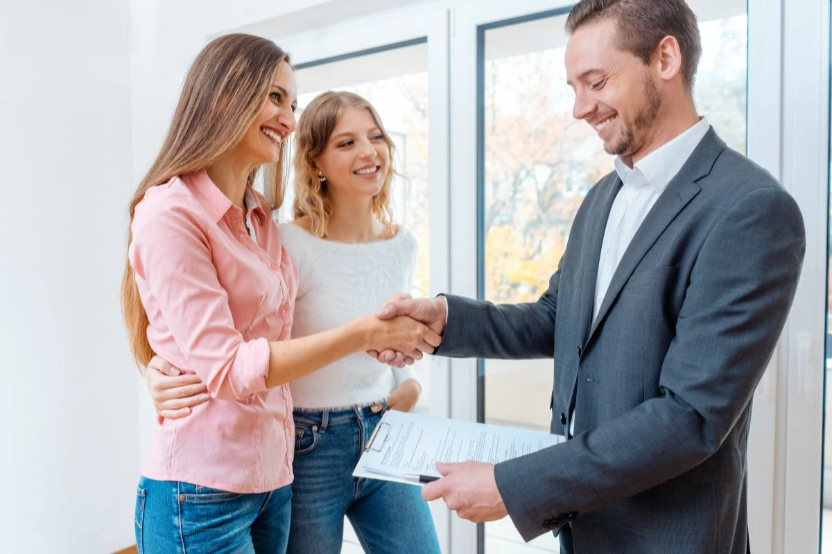 Mère et fille et un professionnel immobilier tenant un document