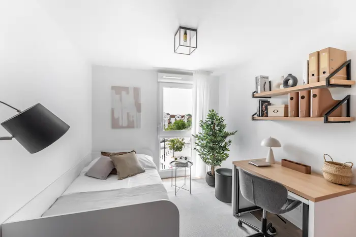 Intérieur d’un logement étudiant social avec espace de travail, lit et rangements — logement adapté aux étudiants en 2026.