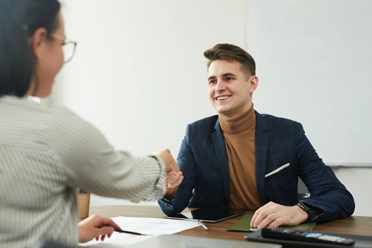 Jeune homme serrant la main d'une professionnelle de l'assurance