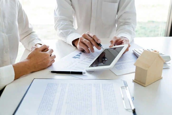 Deux hommes qui consultent une tablette devant des documents.