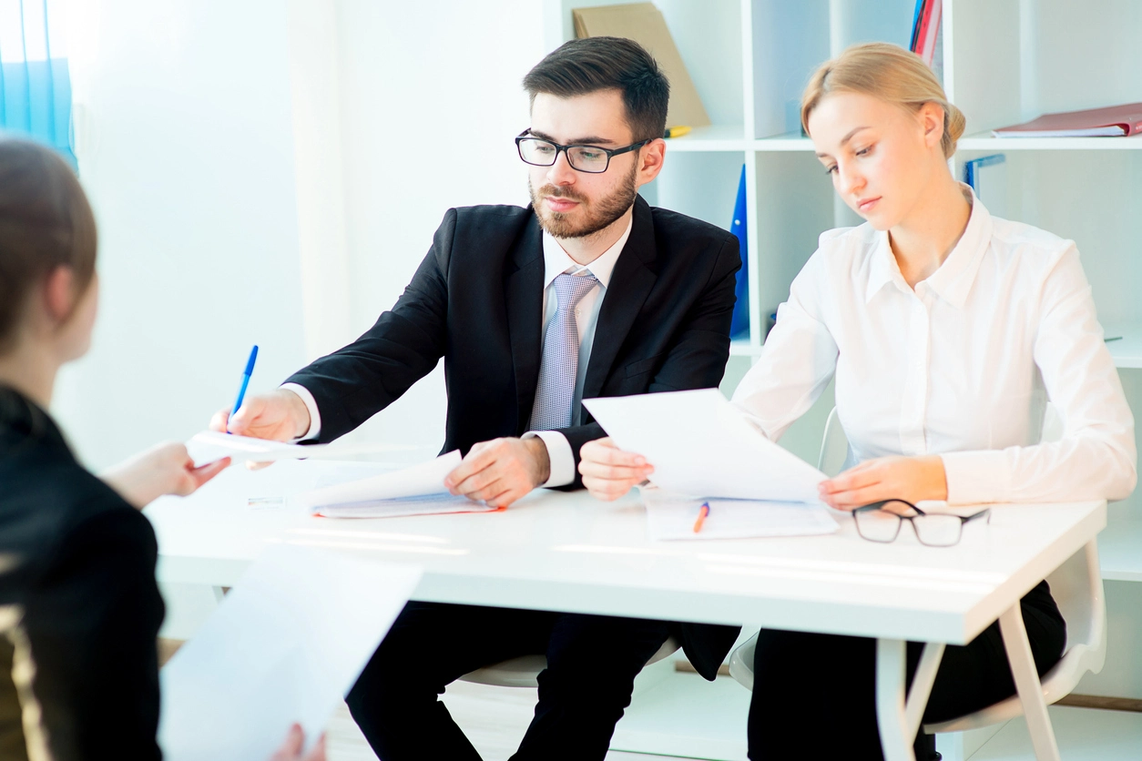 Jeune femme assise devant deux adultes devant un bureau