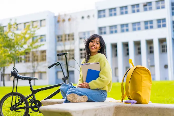 Une étudiante avec un vélo assise sur un banc